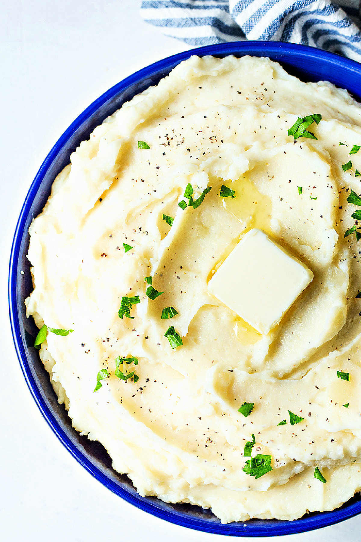 Overhead shot of finished instant pot mashed potatoes in a serving bowl with a pat of butter on top.