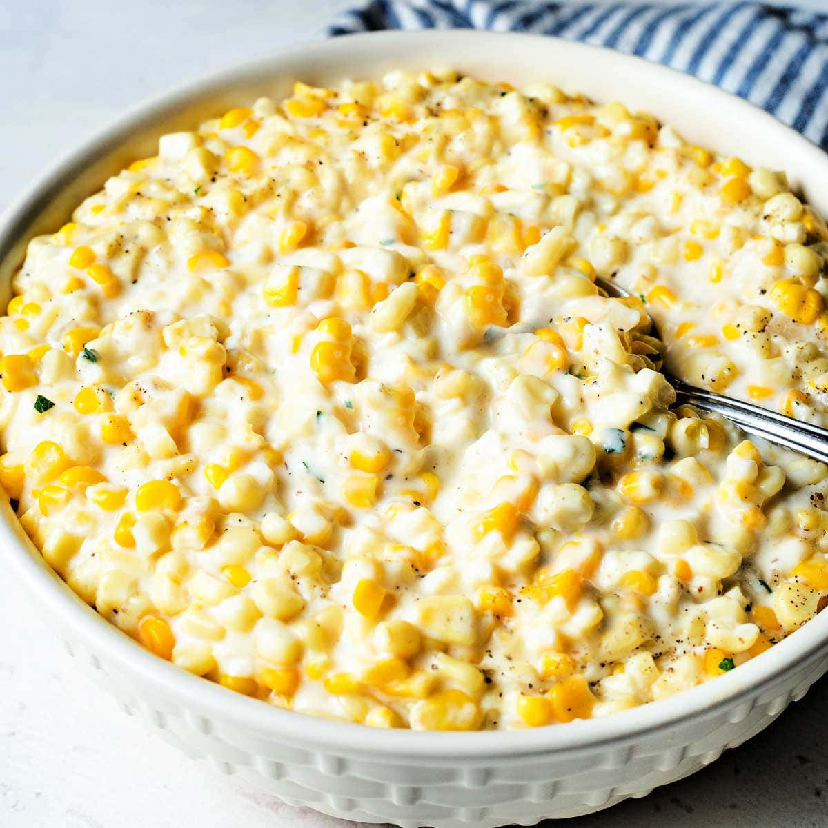 Creamed corn in a large bowl with a serving spoon.