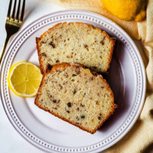 Two slices of lemon bread on a plate with a lemon garnish.