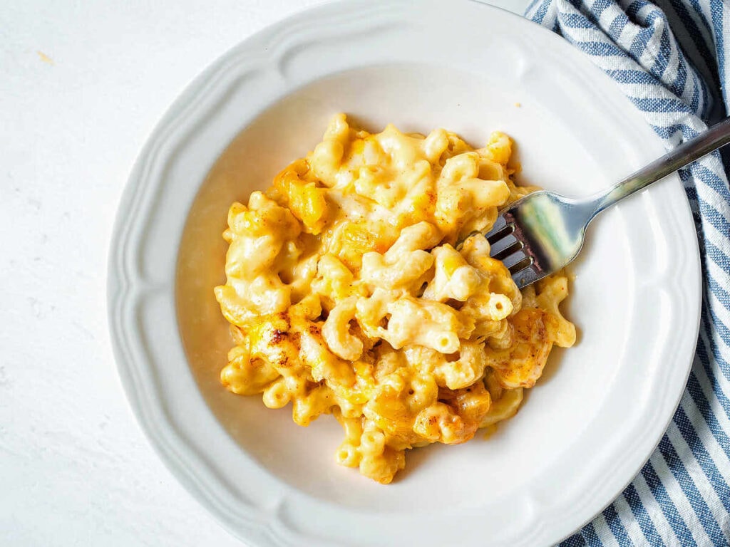 Portion of baked macaroni and cheese served in a bowl with a fork.