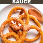SPICY ONION RING DIPPING SAUCE DRIZZLED OVER A PLATE OF ONION RINGS WITH A TEXT OVERLAY.