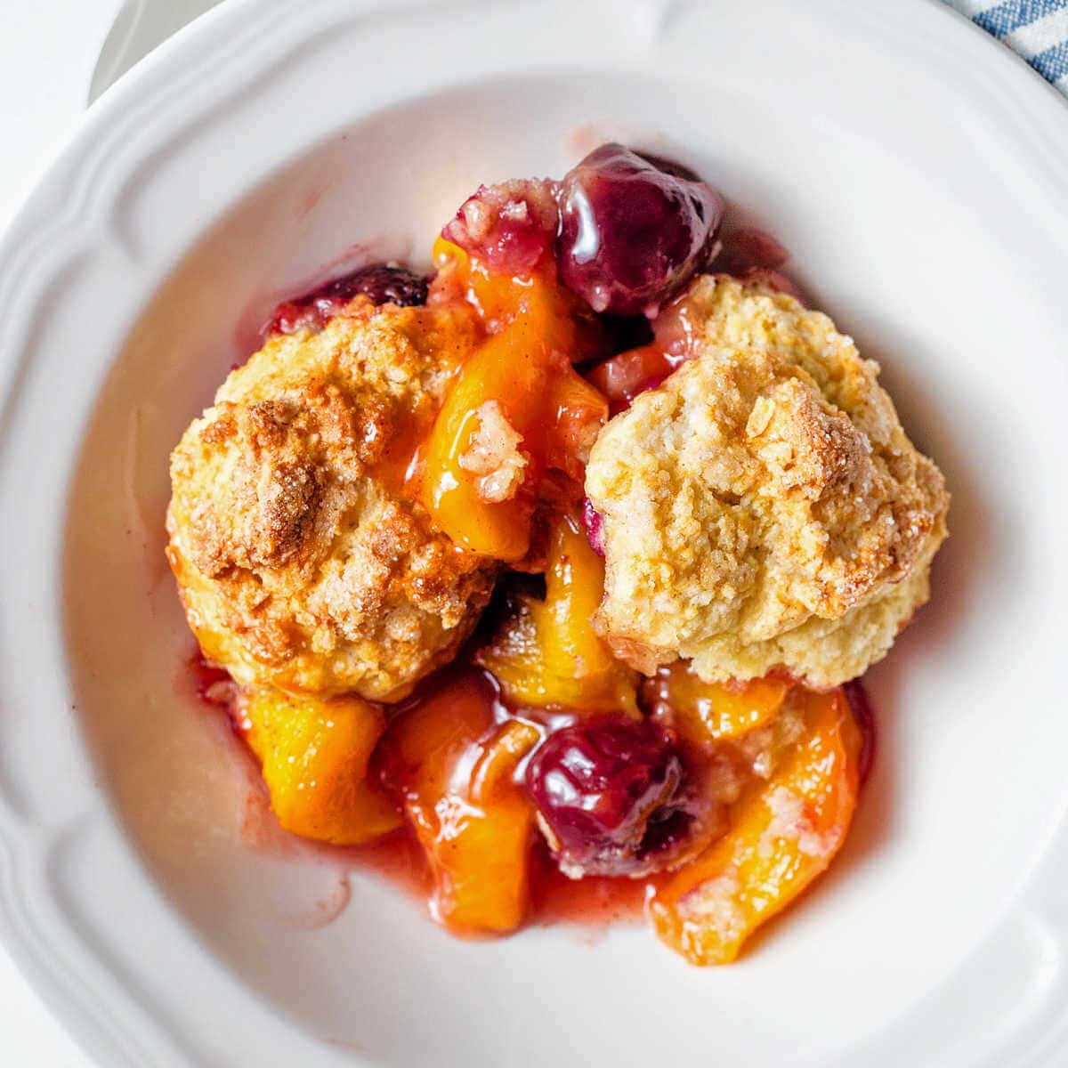 A serving of peach cherry cobbler in a bowl.