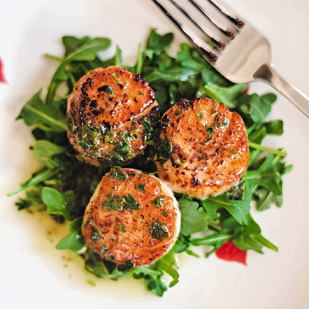 Pan seared scallops on top of a bed of arugula with a lemon butter drizzle on top.